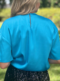 Prepare to dazzle in our Aqua Satin Top - a stunning fusion of vivacity and elegance that's perfect for making a bold and unforgettable style statement.